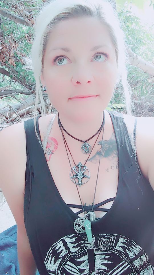white haired woman wearing a tank top and necklaces looking up and away from the camera