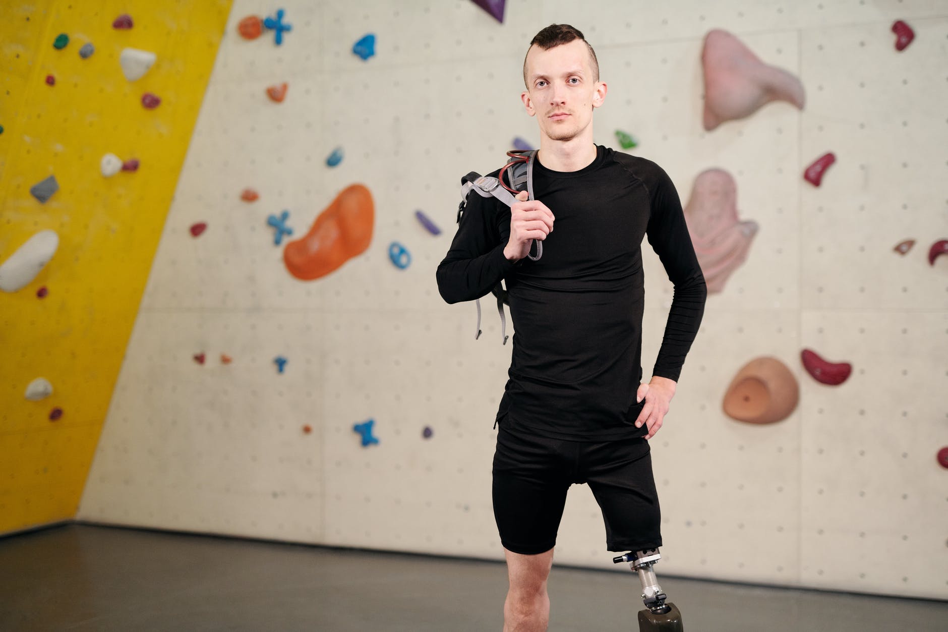 man standing in front of a climbing wall with his gear