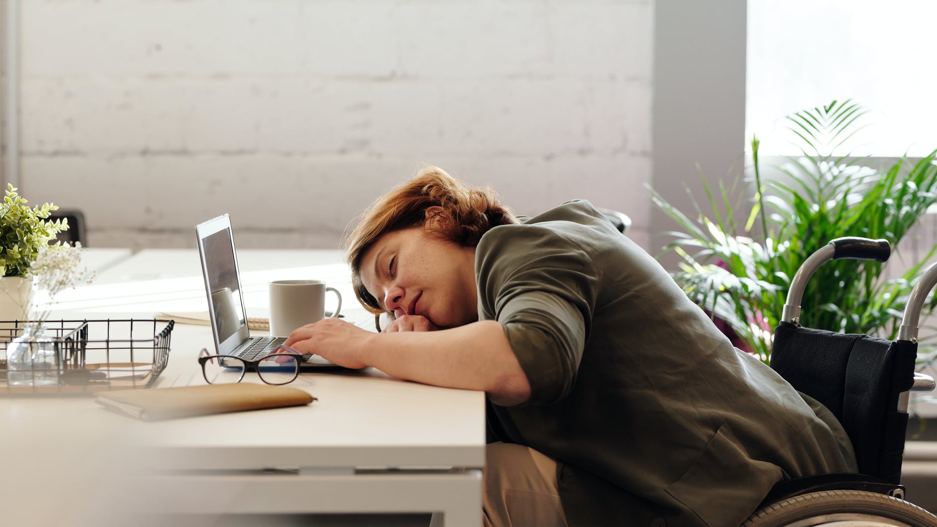 woman sleeping at her desk in front of a laptop