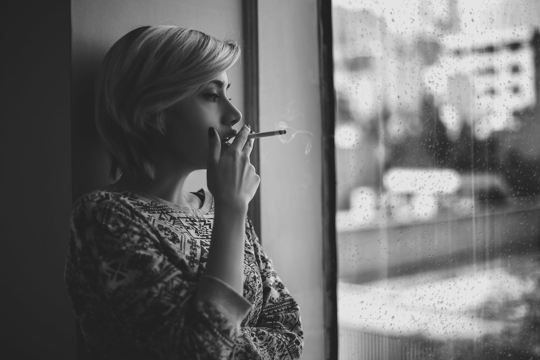 woman smoking in front of a window